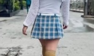 Braless brunette in a miniskirt walking the city streets.